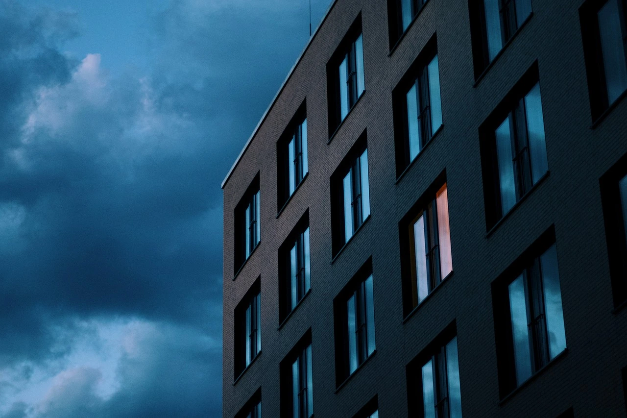 Mehrfamilienhaus mit Aluminiumfenstern vor dunklem Abendhimmel